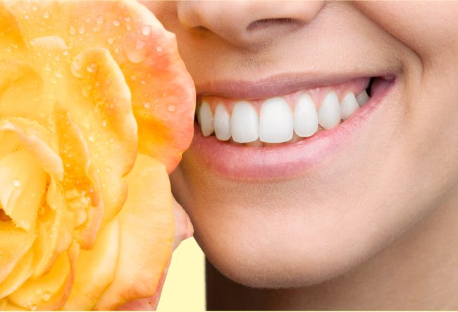 Unwanted Hair Removal woman's white teeth smile next to yellow rose