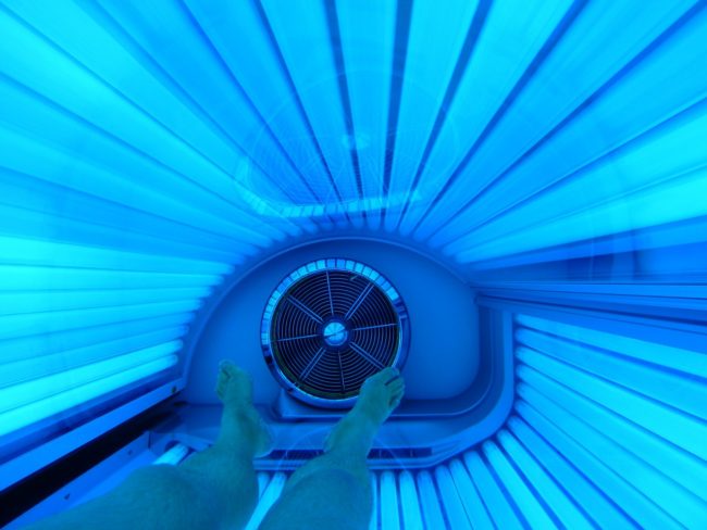 woman laying inside tanning bed