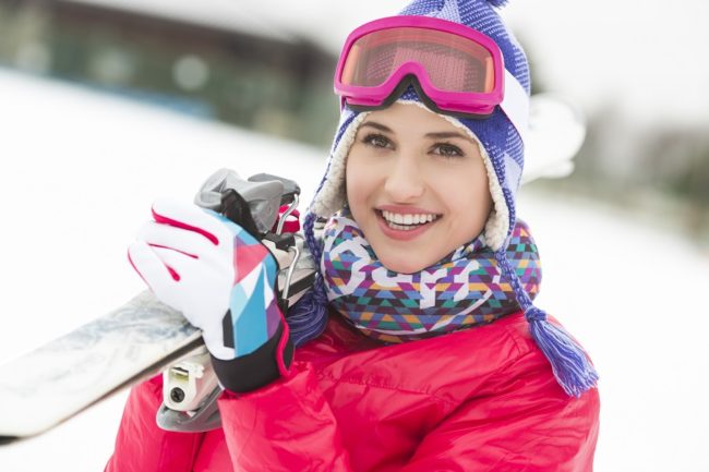 How to Prevent Frostbite female holding skis, wearing scarf, ski jacket, gloves, goggles and hat