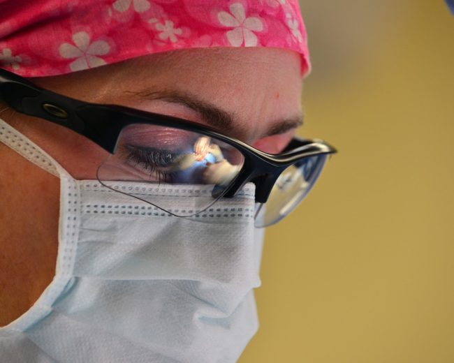 dermatologist with mask and glasses on performing excision of melanoma