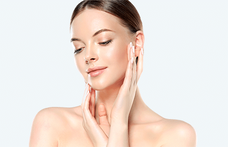 A woman looking down towards the ground, touching both sides of her face